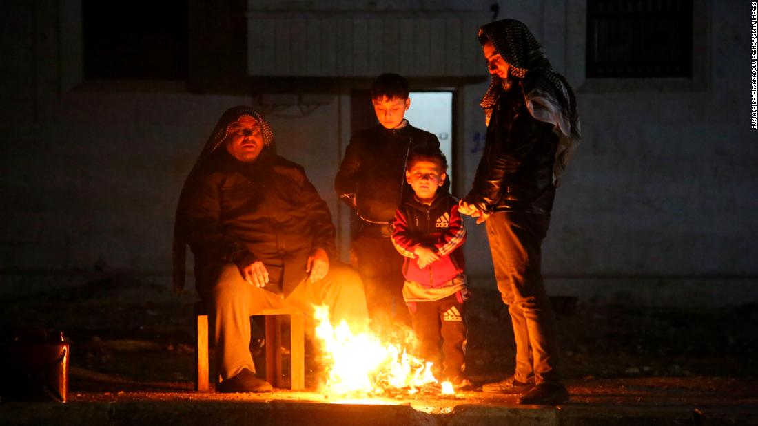 People warm themselves outside of earthquake-affected areas in Aleppo on February 6.