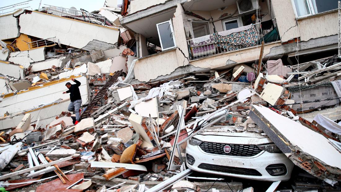 A person climbs through the rubble of a collapsed building in Hatay.