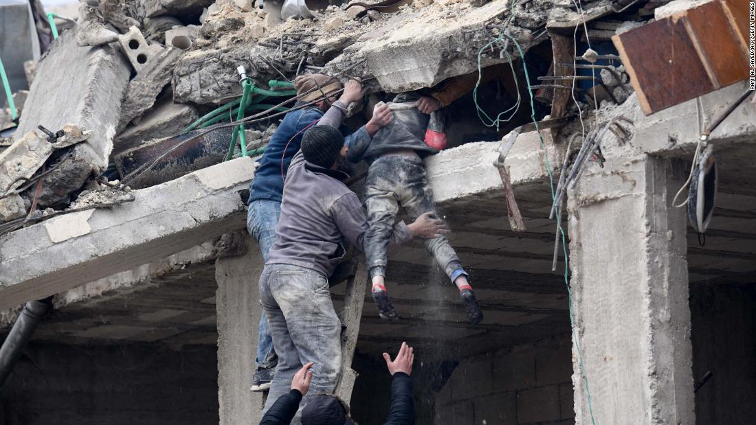 Residents rescue an injured girl from the rubble of a collapsed building in Jandaris on February 6.