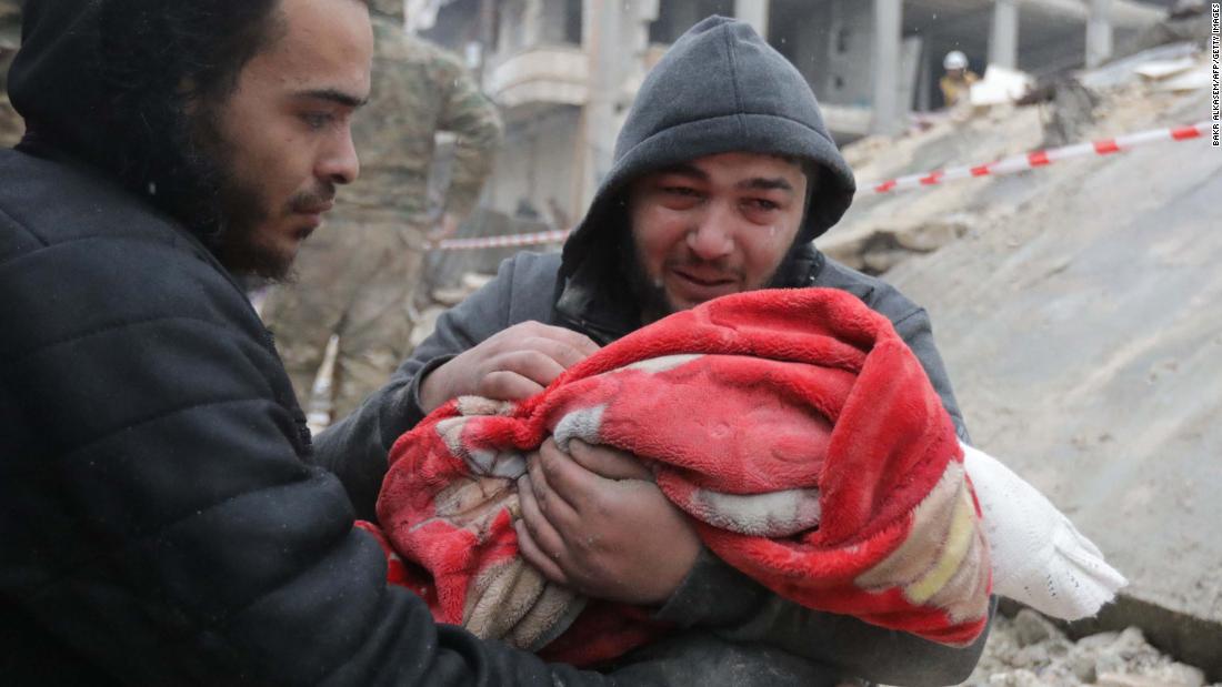 A man weeps as he carries the body of his infant son who was killed in Jandaris.