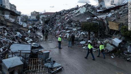 People walk past destroyed buildings in Iskenderun, Turkey, on Tuesday.
