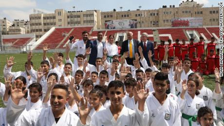 International Olympic Committee President Thomas Bach, back right, and President of the Palestine Olympic Committee Jibril Rajoub, second right, back, meet with young Palestinian athletes at Faisal Al-Husseini stadium in the West Bank city of Al-Ram, north of Jerusalem, in September 2022.