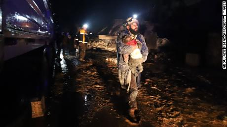 TOPSHOT - A member of the Syrian civil defence, known as the White Helmets, carries a child rescued from the rubble following an earthquake in the town of Zardana in the countryside of the northwestern Syrian Idlib province, early on February 6, 2023. - A 7.8-magnitude earthquake hit Turkey and Syria on February 6, killing hundreds of people as they slept, levelling buildings, and sending tremors that were felt as far away as the island of Cyprus and Egypt. (Photo by Abdulaziz KETAZ / AFP) (Photo by ABDULAZIZ KETAZ/AFP via Getty Images)