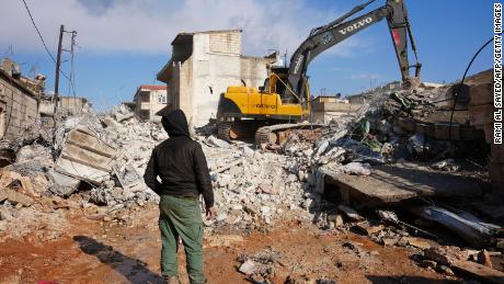 A Syrian boy watches as an excavator goes through the rubble of a building where the baby was found.