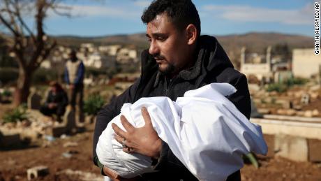 A man carries the body of one of the baby&#39;s family members for burial.