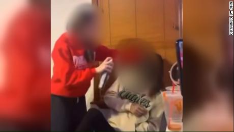A screenshot from a video that circulated online Tuesday showing a student using black spray paint on another student&#39;s face. 