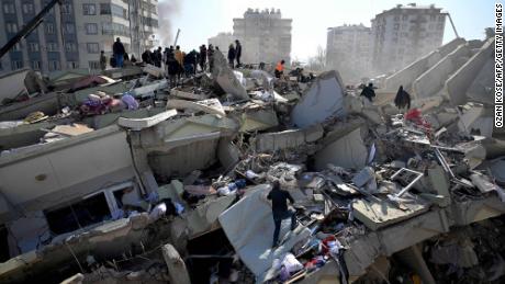 Families of victims stand as rescue officials search among the rubble of collapsed buildings in Kahramanmaras, on February 9, 2023, three days after a 7,8-magnitude earthquake struck southeast Turkey. - The death toll from a huge earthquake that hit Turkey and Syria climbed to more than 17,100 on on February 9, as hopes faded of finding survivors stuck under rubble in freezing weather. (Photo by OZAN KOSE / AFP) (Photo by OZAN KOSE/AFP via Getty Images)