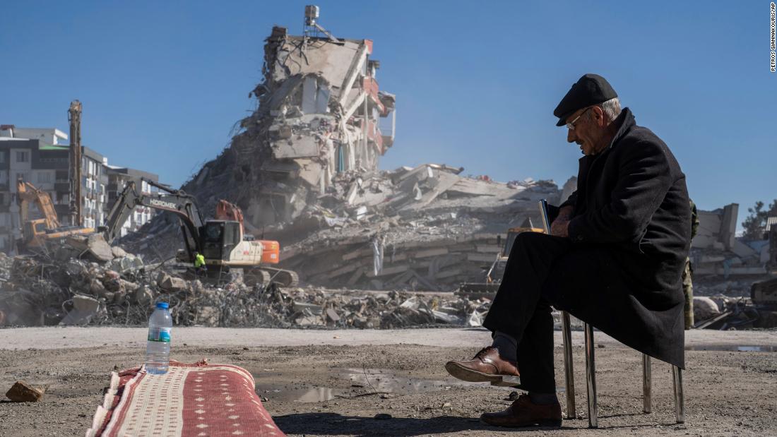 Mehmet Nasir Duran sits on a chair as heavy machines remove debris from a building where five of his family members were trapped in Nurdagi, Turkey, on February 9.