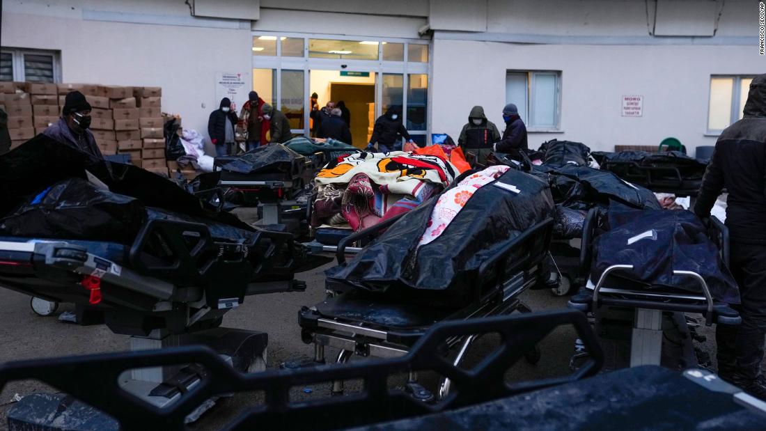 People stand next to the dead bodies of earthquake victims in Elbistan on February 9.