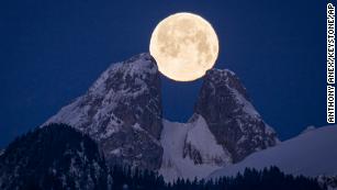 The full moon sets behind the mountains including the twin peaks of Les Jumelles in the Chablais Valaisan, near Aigle, Switzerland, Monday, 6 Feb. 2023. (Anthony Anex/Keystone via AP)