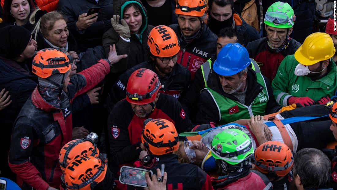 Raziye Kilinc is carried through a crowd on a stretcher after she was rescued from a destroyed building in Iskenderun, Turkey, on February 10. Her daughter is seen waving at the top.
