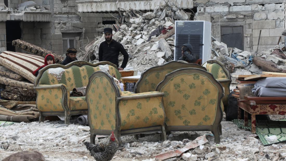 People sit on furniture outside damaged buildings in Jandaris, Syria, on February 10.