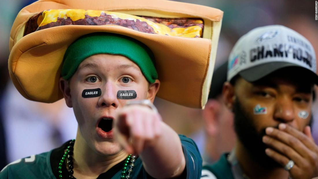 An Eagles fan with a cheesesteak hat gestures at the camera during pregame warmups.