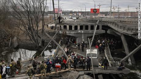 Residents cross a destroyed bridge as they evacuate the city of Irpin, northwest of Kyiv, during heavy shelling and bombing on March 5, 2022.