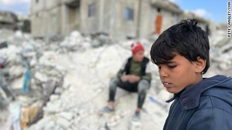 A child stands in the rubble that remains of his former home. Twenty-one members of his family died in the earthquake.