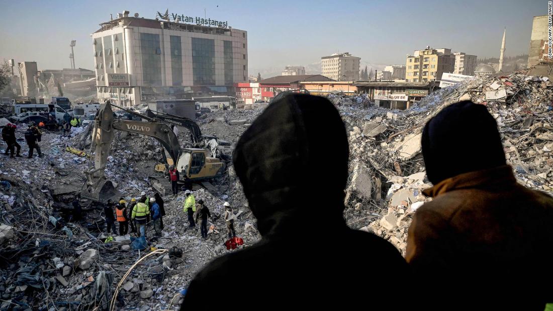 People wait near a collapsed building in Kahramanmaras, Turkey, hoping for news of their missing relatives on February 14.