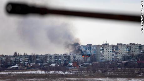 A Ukrainian military vehicle drives by as an apartment building hit by Russian artillery burns in the distance on February 14, 2023 in Bakhmut, Ukraine.
