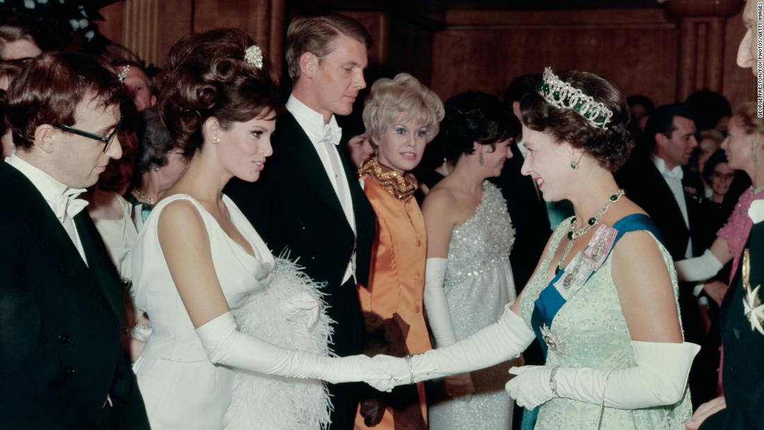 Welch shakes hands with Britain&#39;s Queen Elizabeth II at a Royal Film performance in 1966. At left is director Woody Allen.