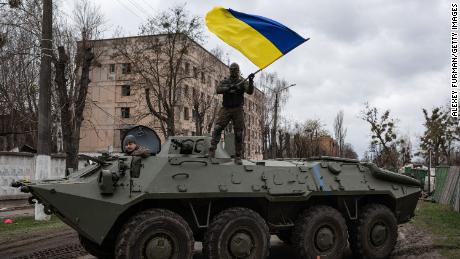 Ukrainian soldier waves Ukrainian national flag while standing on top of an armoured personnel carrier (APC) on April 8, 2022 in Hostomel, Ukraine. After more than five weeks of war, Russia appears to have abandoned its goal of encircling the Ukrainian capital. However, Ukraine expects a renewed fight in the east and south. 