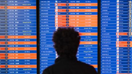 Travelers look at an information board showing flight cancellations and delays at Reagan National airport during a winter storm ahead of the Christmas holiday in Arlington, Virginia, on December 23, 2022.