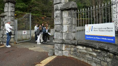 People stand at the entrance of the Saint-Thomas d&#39;Aquin school in Saint-Jean-de-Luz, France, where a teacher died after being stabbed by a student, on February 22, 2023.