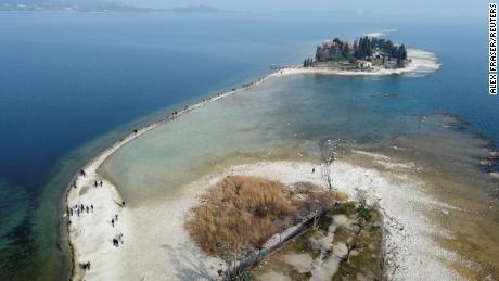 People walk to San Biagio Island along a strip of land that was previously submerged, at Lake Garda in northern Italy, on February 21.