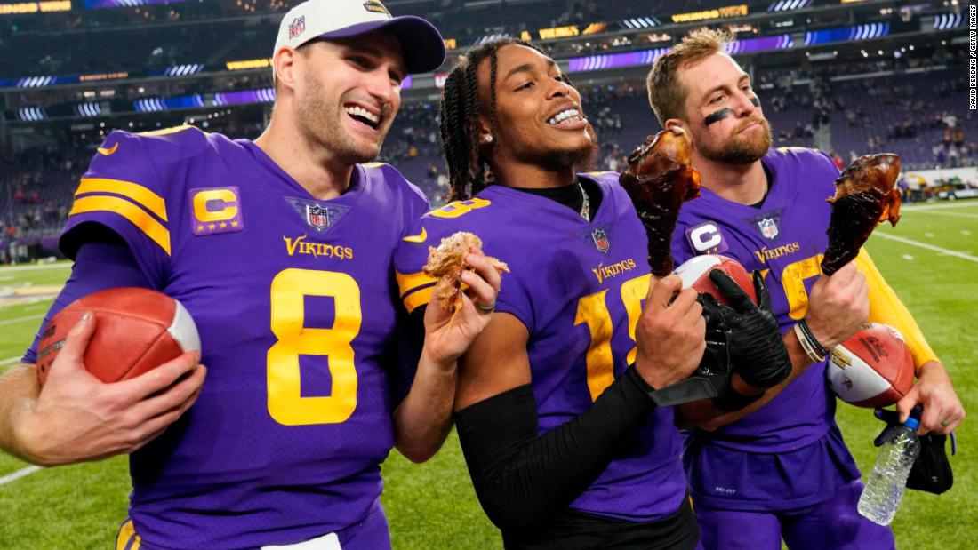Minnesota Vikings trio Kirk Cousins, Justin Jefferson, and Adam Thielen celebrate a Thanksgiving Day victory over the New England Patriots in 2022 by eating turkey legs. The tradition is a homage to legendary coach John Madden, who awarded the first &quot;Turkey Leg Award&quot; to Thanksgiving Day MVP Reggie White in 1989, while working for CBS.