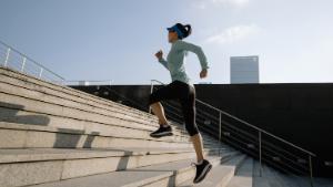 Fitness sports woman running up stairs in city.