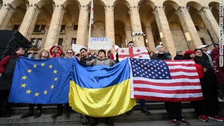 People hold flags of the Europan Union, Ukraine and the US during a demonstration outside Georgia&#39;s Parliament in Tbilisi on March 8.