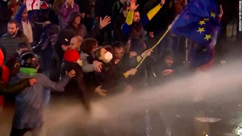Protesters shield woman waving EU flag amid clash with police