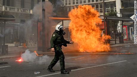 A Greek riot policeman walks past an exploded molotov during a demonstration. 
