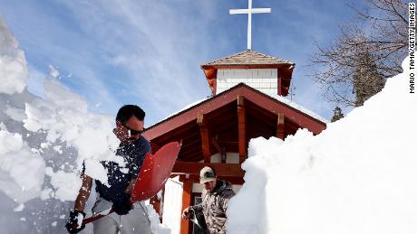 Residents shovel snow from in front of a church after a series of winter storms dropped more than 100 inches of snow in the San Bernardino Mountains in Southern California on March 8, 2023 in Twin Peaks, California. 