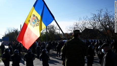 A man holds Moldovan national flag as special police officers patrol a street near a polling station during the second round of Moldova&#39;s presidential election in the town of Varnita.