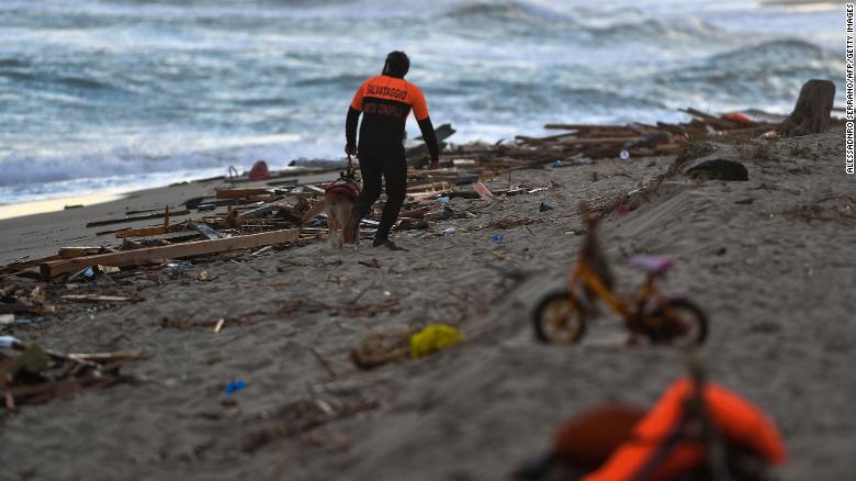 A policeman and his dog patrol the beach on February 26, 2023, where debris of a shipwreck was washed ashore after a migrants&#39; boat sank off Italy&#39;s southern Calabria region.