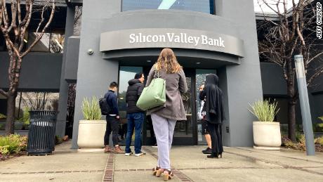 People stand outside of an entrance to Silicon Valley Bank in Santa Clara, Calif., Friday, March 10, 2023. The Federal Deposit Insurance Corporation seized the assets of the bank on Friday, marking the largest bank failure since Washington Mutual during the height of the 2008 financial crisis. 