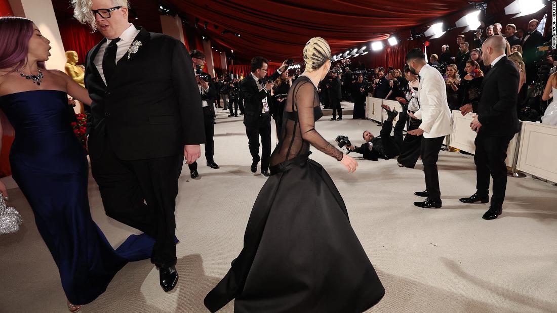 Lady Gaga looks back at a photographer who fell on the champagne-colored &lt;a href=&quot;http://www.cnn.com/style/article/oscars-red-carpet-fashion-2023/index.html&quot; target=&quot;_blank&quot;&gt;red carpet&lt;/a&gt; before the show. The singer went back to help the man up.