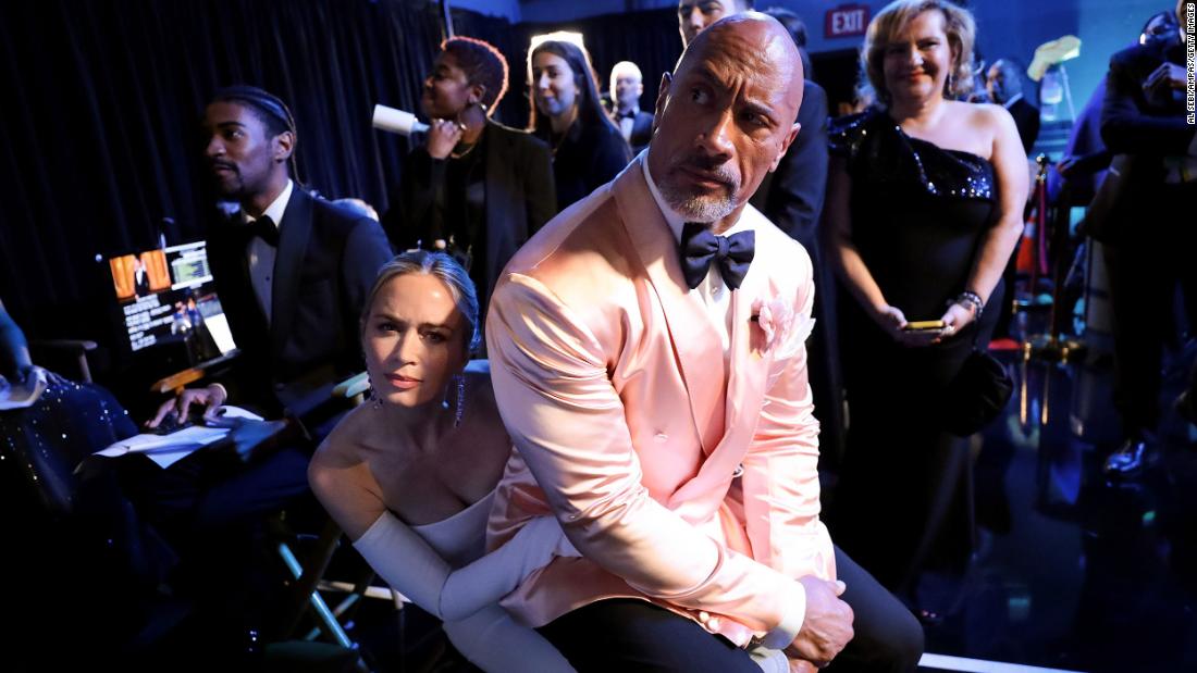 Dwayne Johnson sits on Emily Blunt&#39;s lap backstage. The two presented an award together during the show.