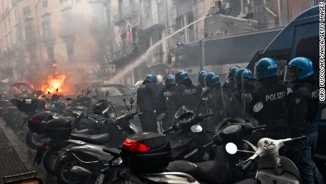 Anti-riot police move beside a truck, extinguishing the blaze of a police car.