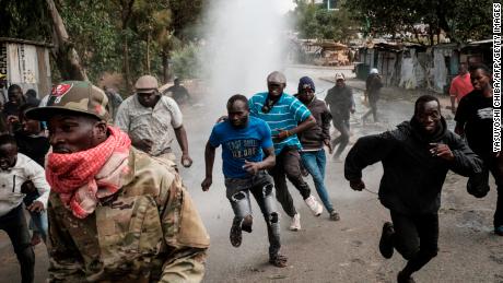 Protesters run away from water released by a police water cannon vehicle during a mass rally called by the opposition leader Raila Odinga in Kibera, Nairobi, Monday.