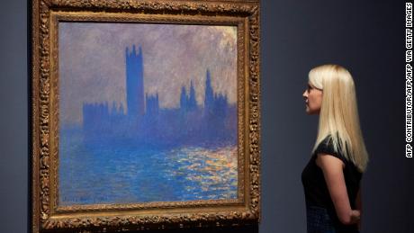 A woman poses by a painting of the Houses of Parliament by French artist Claude Monet during a press preview for the exhibition French Artists in Exile (1870-1904) at Tate Britain in London on October 30, 2017  / AFP PHOTO / NIKLAS HALLE&#39;N / RESTRICTED TO EDITORIAL USE - MANDATORY MENTION OF THE ARTIST UPON PUBLICATION - TO ILLUSTRATE THE EVENT AS SPECIFIED IN THE CAPTION        (Photo credit should read NIKLAS HALLE&#39;N/AFP via Getty Images)