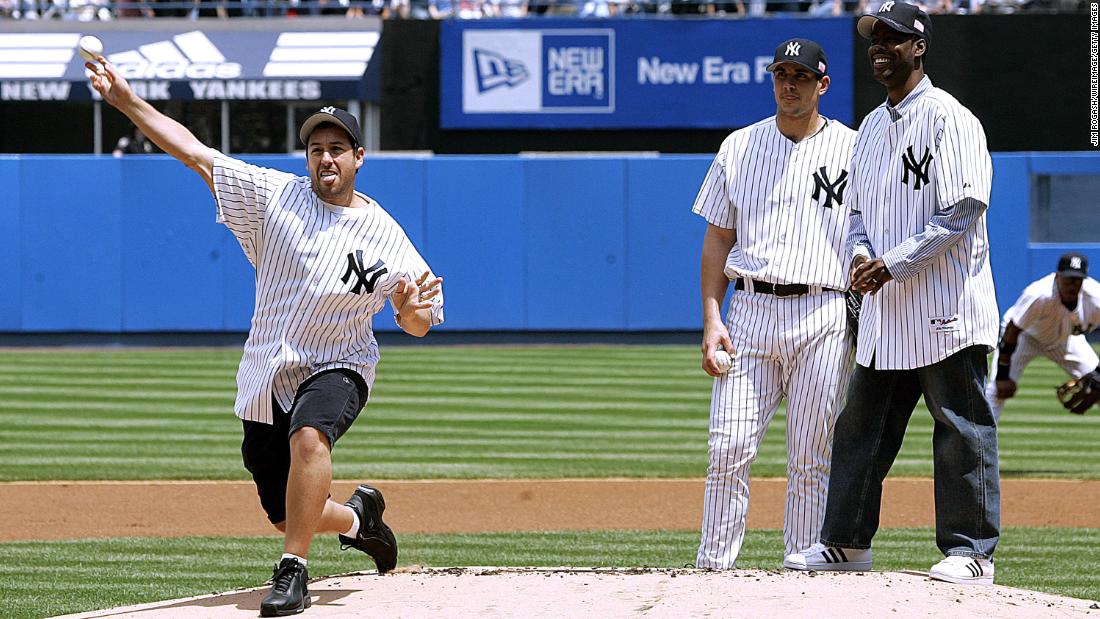 Sandler throws a pitch at Yankee Stadium before a Major League Baseball game in New York in May 2005. At right are Chris Rock and Yankees pitcher Carl Pavano.