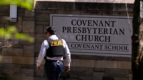 A police officer walks by an entrance to The Covenant School after a shooting in Nashville, Tenn. on Monday, March 27, 2023.  (AP Photo/John Amis)