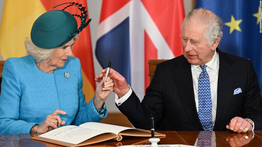 The King and Camilla, the Queen Consort, sign a guest book Wednesday at the palace.