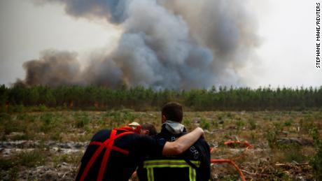 Firefighters embrace as they work to contain a fire in Saint-Magne in southwest France in August 2022.