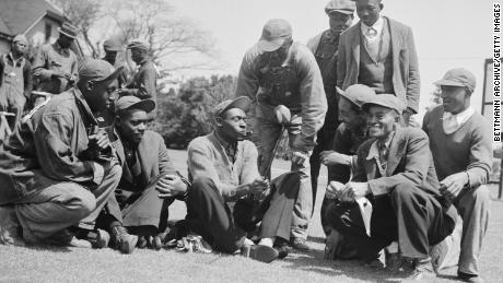 John H. &quot;Stovepipe&quot; Gordon (center), caddie for Gene Sarazen, shows fellow caddies the club Sarazen made a double eagle with at the 1935 Masters.