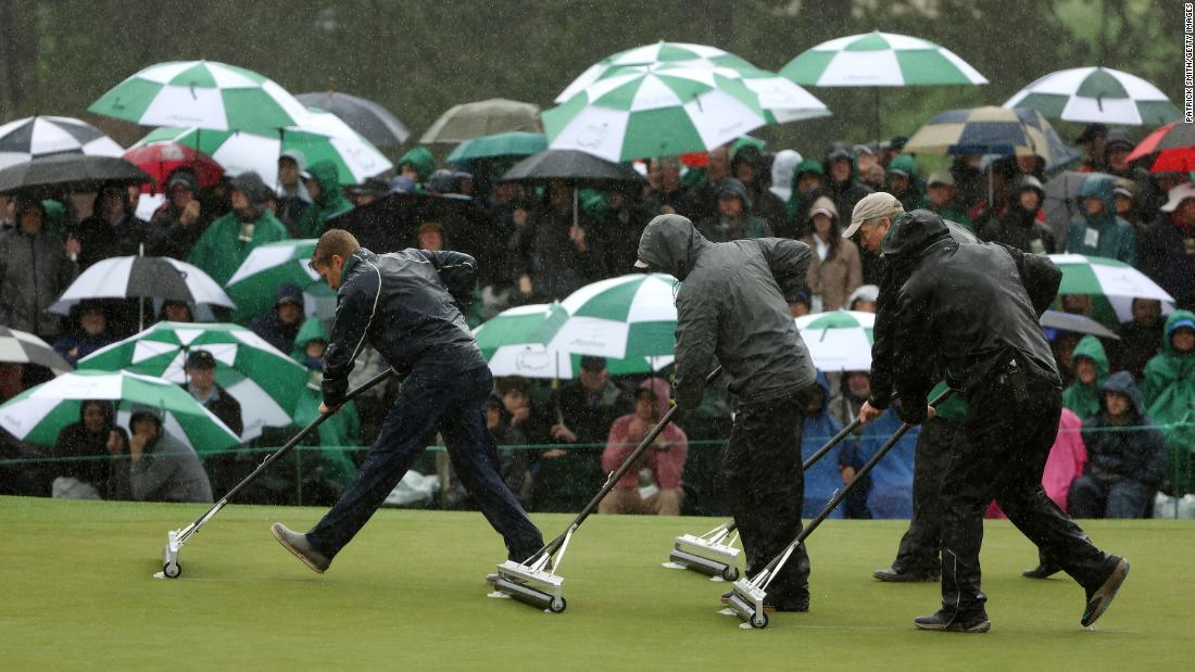 Groundskeepers remove standing water on green during the continuation of the weather-delayed second round on Saturday. 