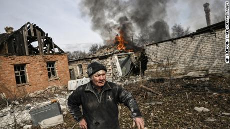 A man stands outside a burning house after shelling in the town of Chasiv Yar, near Bakhmut, on March 21, 2023. 