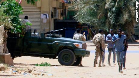 People run past a military vehicle in Khartoum on April 15, 2023, amid reported clashes in the city. - Sudan&#39;s paramilitaries said they were in control of several key sites following fighting with the regular army on April 15, including the presidential palace in central Khartoum. (Photo by AFP) (Photo by -/AFP via Getty Images)