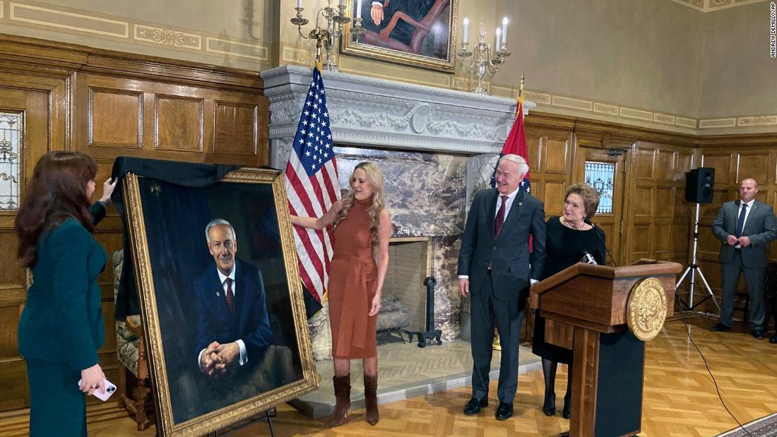 Hutchinson and his wife, Susan, watch as their granddaughter, Jaella Wengel, left, and daughter, Sarah Wengel, unveil his official portrait at the State Capitol in January 2023.