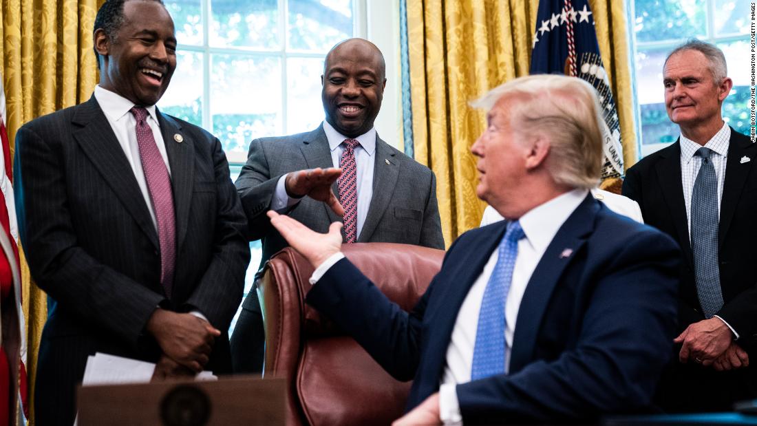 Trump reaches out to Scott in June 2019 as he signs an executive order establishing a White House Council on eliminating regulatory barriers to affordable housing. At left is former Housing and Urban Development Secretary Ben Carson.